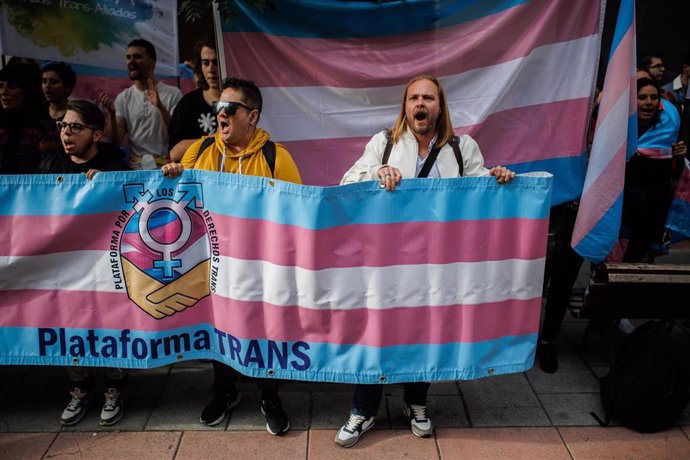 Varias personas con una banderas trans durante una concentración de la Federación Plataforma Trans, en la sede del PSOE en la calle Ferraz, a 28 de octubre de 2022, en Madrid (España). La Federación Plataforma Trans se concentra para protestar contra la