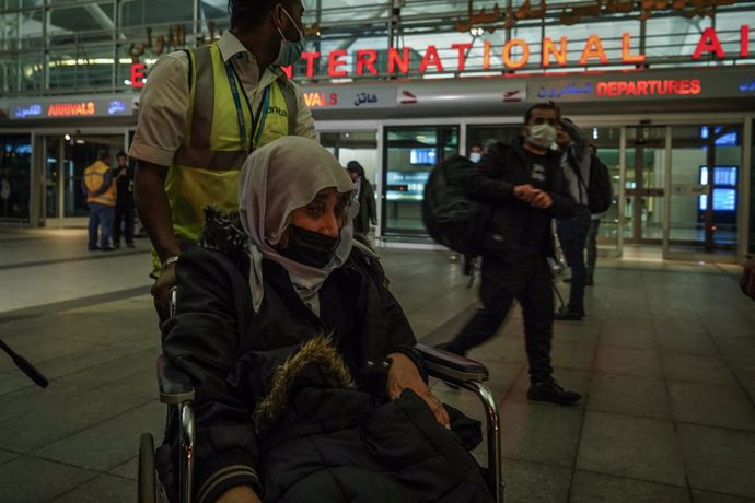 Archivo - 18 November 2021, Iraq, Erbil: A man pushes an elderly woman on a wheelchair after landing at the Erbil International Airport on board a repatriation flight that was sent by the Iraqi government to pick up migrants who were stranded for weeks 