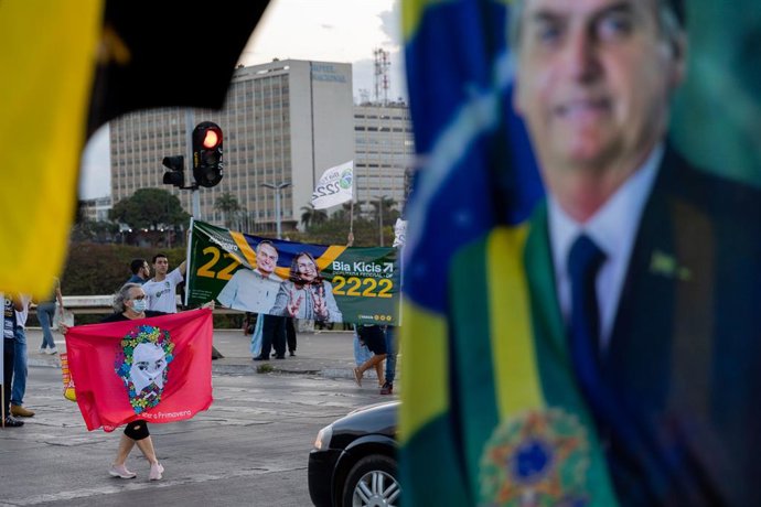 Archivo - FILED - 26 September 2022, Brazil, Brasilia: Supporters of current President Bolsonaro and former head of state Lula da Silva promote their candidates with flags and posters in front of motorists at a red light. General elections are scheduled