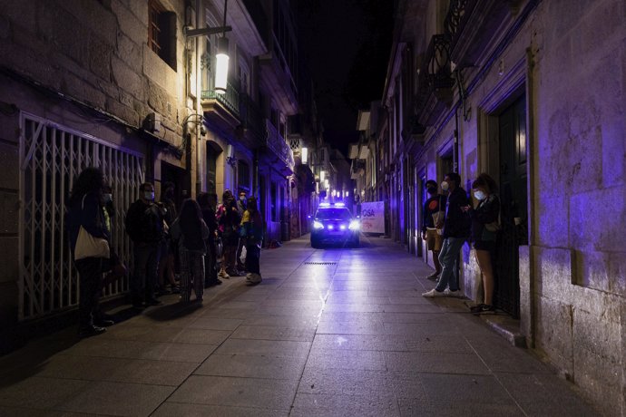 Un coche de policía pasa frente a varias personas en ambiente festivo, a 10 de julio de 2021, en Pontevedra, Galicia (España).