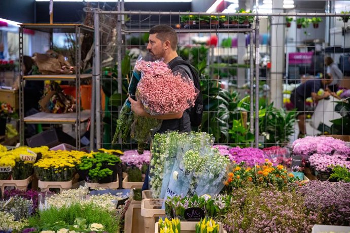 Un home sosté diversos rams de flors a Mercabarna.