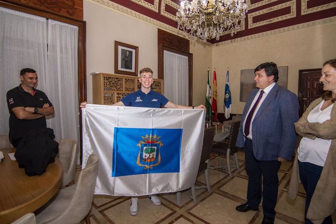 Cruz recibe en el Consistorio al piloto onubense Paquito Gómez, campeón de España de Supermotard, que porta la bandera de la ciudad.