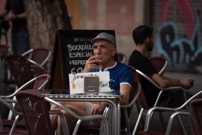 Archivo - Un hombre fuma sentado en la mesa de una terraza que una nueva normativa convertirá en espacio libre de humo por el Govern, en plaza de la Vila de Grcia, a 23 de septiembre de 2022, en Barcelona, Catalunya (España). La nueva normativa consist