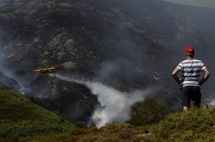 Archivo - Un vecino de Senderiz en Lobeira observa un hidroavión trabajar en el incendio forestal en la Serra do Leboreiro, sobrevuela una explotación ganadera, en el parque natural de Baixa Limia e Serra do Xurés, a 26 de agosto de 2022, en Serra do Xu