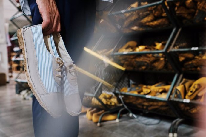 Archivo - Un hombre sostiene unos zapatos frente a una tienda.