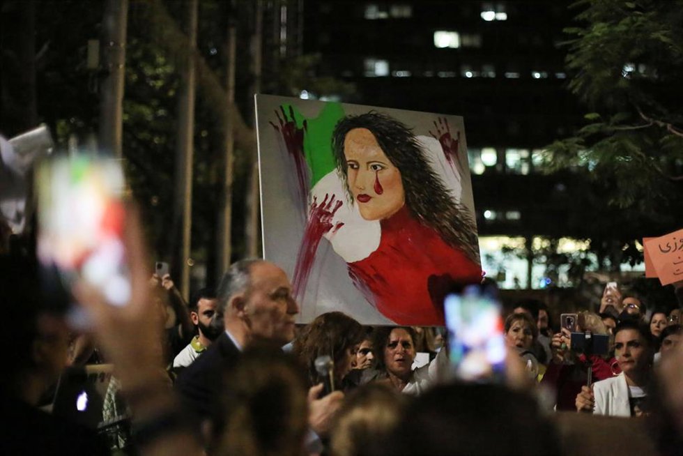 Manifestantes sostienen carteles y banderas iraníes mientras protestan contra la muerte de Masha Amini
