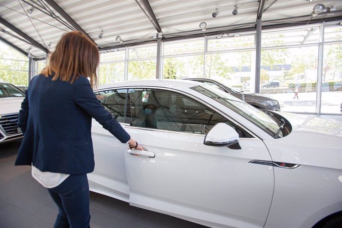 Archivo - Una mujer abre un coche en un concesionario