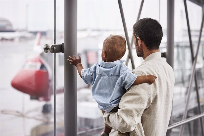 Pasajero aéreo mira con un niño en un aeropuerto un avión de Norwegian