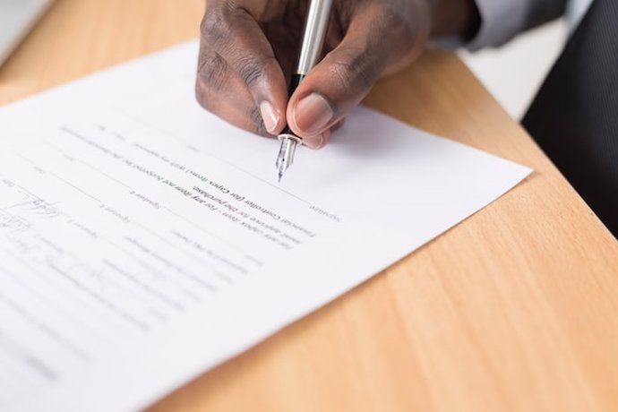 Una persona firmando un documento.