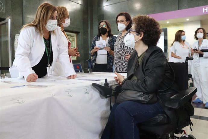 Una cuidadora se acerca a una mesa informativa.