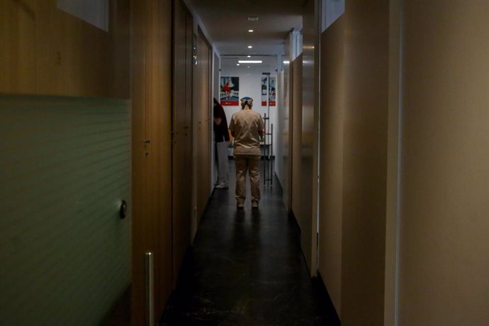 Archivo - Un trabajador pasa por un pasillo de un centro médico, foto de archivo