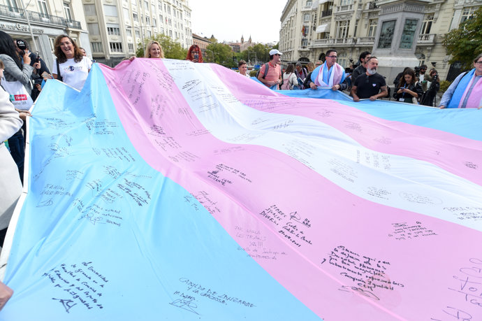 Varias personas sostienen la bandera trans que la Federación Estatal de Lesbianas, Gais, Trans, Bisexuales, Intersexuales y más (Flegtbi+)