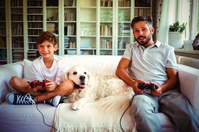 Niño, perro y adulto jugando a videojuegos 