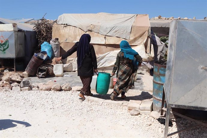 Archivo - Mujeres desplazadas cargan un bidón de agua proporcionado por MSF en el noroeste de Siria