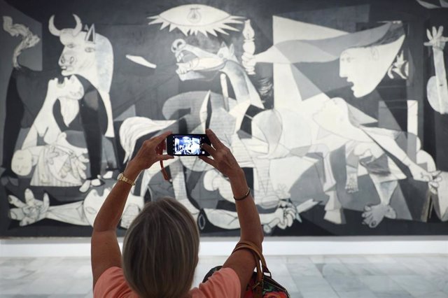 Archivo - Una mujer fotografía la obra de Picasso 'Guernica' en el Museo Reina Sofía