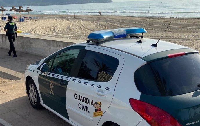 Archivo - Una agente y un vehículo de la Guardia Civil en una playa de Mallorca.