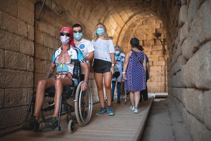 Archivo - Un hombre en silla de ruedas visita un monumento de Mérida.