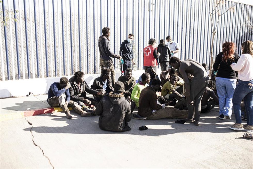 Archivo - Varios migrantes son atendidos por personal de la Cruz Roja tras saltar la de Melilla en marzo
