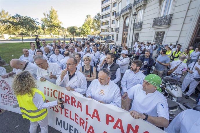 Un grupo de personas pertenecientes al gremio de panaderos y pasteleros de Valencia sostienen una pancarta en una concentración frente a la Delegación del Gobierno para protestar por la crisis del sector