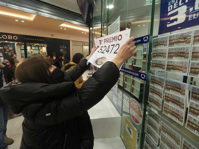 Archivo - Una mujer cuelga un número premiado en un Sorteo Extraordinario de Lotería de Navidad