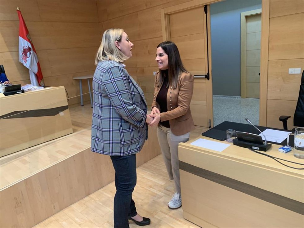 La consejera de Familia, Isabel Blanco, saluda a la procuradora del Grupo Parlamentario Socialista Nuria Rubio antes de comparecer en la Comisión de Economía y Hacienda de las Cortes.