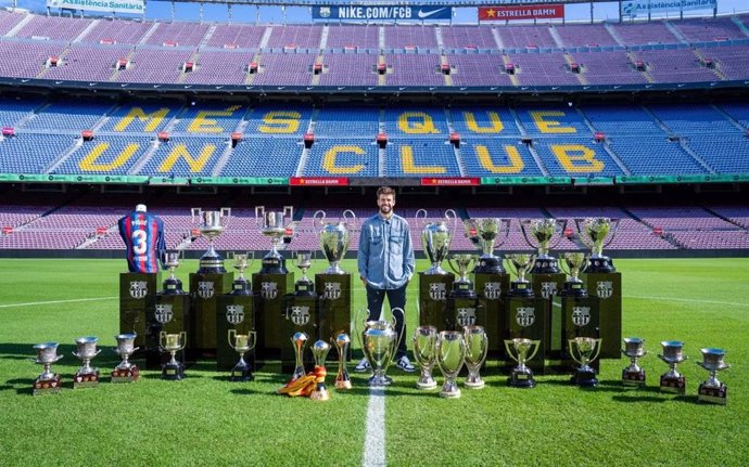 El futbolista Gerard Piqué con los 30 títulos que ganó con el FC Barcelona, en el césped del Camp Nou