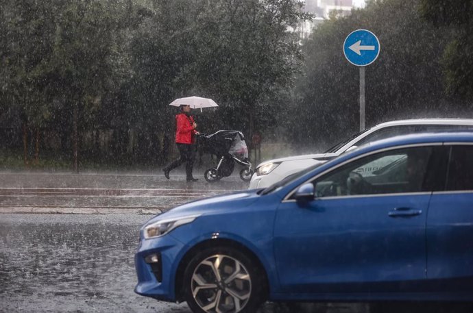 Una mujer lleva un carrito de bebé mientras se protege de la lluvia con un paraguas, a 11 de noviembre de 2022, en Valncia