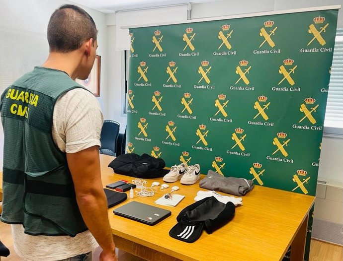 Un agente de la Guardia Civil junto con los objetos robados.