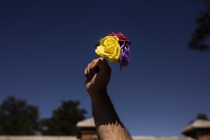 Archivo - Un hombre levanta tres rosas de los colores de la bandera republicana durante un homenaje a las 13 Rosas y los 43 Claveles en el 82 aniversario de su fusilamiento, en el Cementerio de la Almudena, a 5 de agosto de 2021, en Madrid (España). Fo