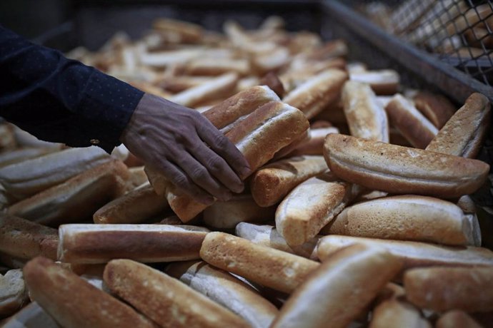 Archivo - 22 March 2022, Yemen, Sanaa: A Yemeni baker collects freshly baked bread at a bakery in the city of Sanaa. Wheat prices have risen sharply on world markets in the wake of the Russian attack on Ukraine, putting more pressure on the already dire