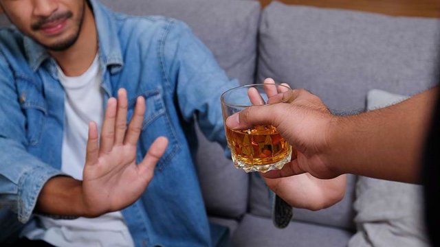 Imatge d'una persona oferint una beguda alcohòlica a una altra