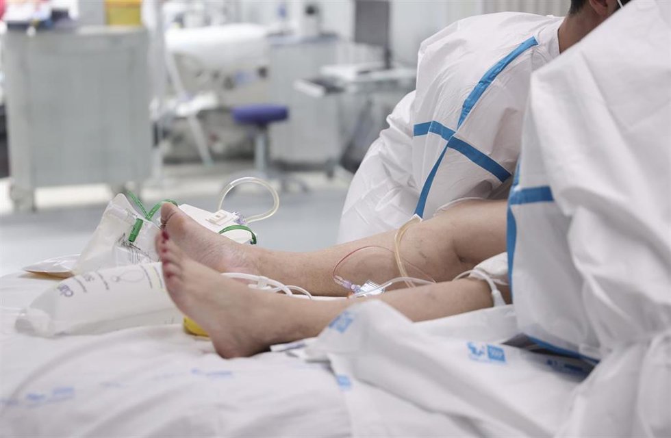 Archivo - Dos enfermeros atienden a una paciente hospitalizada