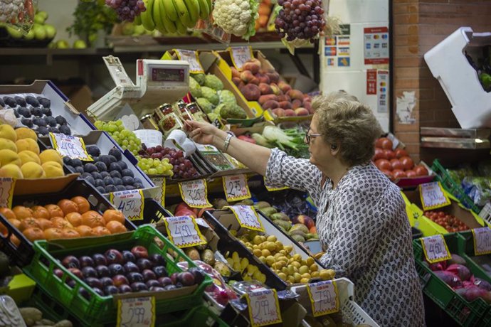 Archivo - Una mujer compra en uno de los puestos del mercado de abastos de Triana, en Sevilla (Foto de archivo).