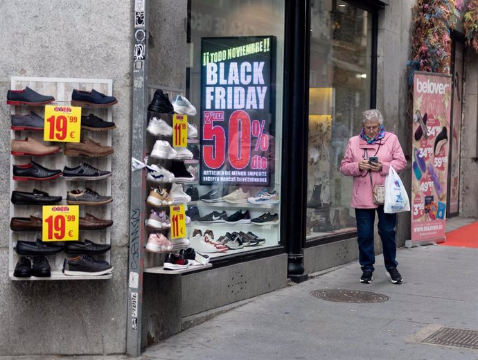 Una mujer pasa por delante de una tienda que anuncia un cartel publicitario del Black Friday, a 14 de noviembre de 2022, en Madrid (España). 