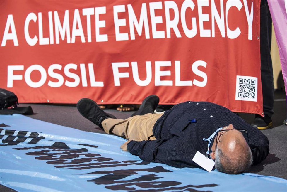 11 November 2022, Egypt, Sharm El-Sheikh: A Climate activist lies on the ground as he takes part in a protest against fossil fuels during the 2022 United Nations Climate Change Conference COP27. Photo: Gehad Hamdy/dpa