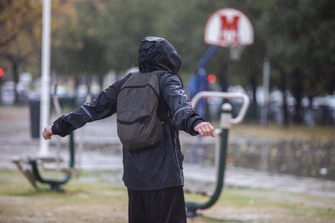 Archivo - Una persona con un chubasquero bajo la lluvia