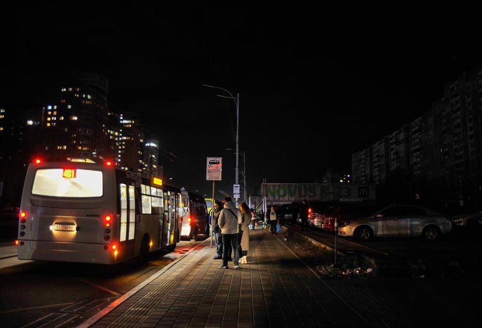 Personas paradas en una parada de transporte público en un Kiev sin luz.