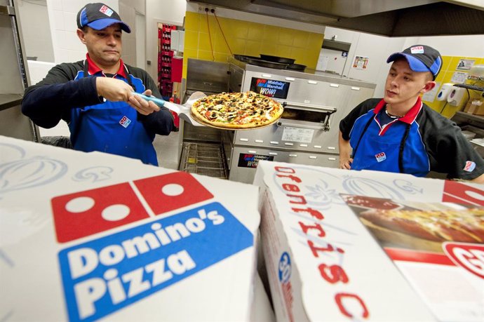 Archivo - FILED - 04 November 2010, Berlin: A staff member of US pizza chain Domino Pizza hands a pizza to a customer in the chain's first German chain store in Berlin. Photo: Robert Schlesinger/dpa-Zentralbild/dpa