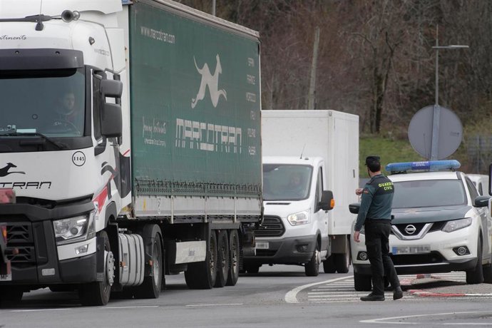 Archivo - Un agente de la Guardia Civil dirige el tráfico de camiones en dirección a la Autovía A6