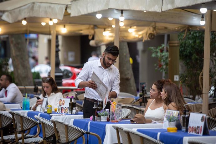 Archivo - Un camarero de origen extranjero atiende una mesa de un bar en Barcelona