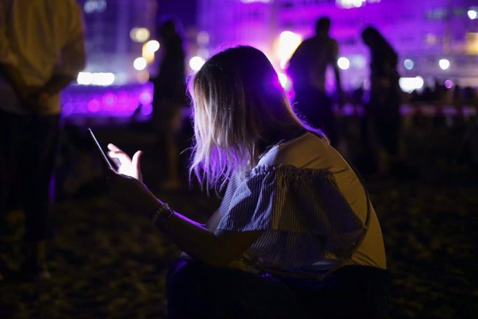 Archivo - Una mujer utiliza su teléfono móvil durante la llegada de Maruxaina a la Praia do Torno en las fiestas de la Maruxaina, a 14 de agosto de 2022, en Cervo, Lugo, Galicia (España). El municipio lucense de Cervo refuerza este año la seguridad para