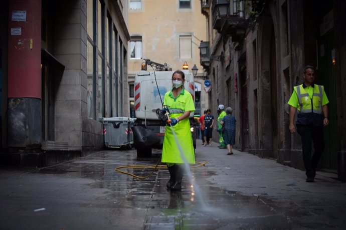 Archivo - Una trabajadora limpia una vía de Barcelona.