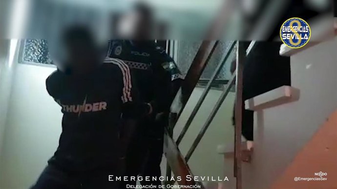 Un agente conduce al detenido hacia el exterior del edificio al que accedió durante su huida.