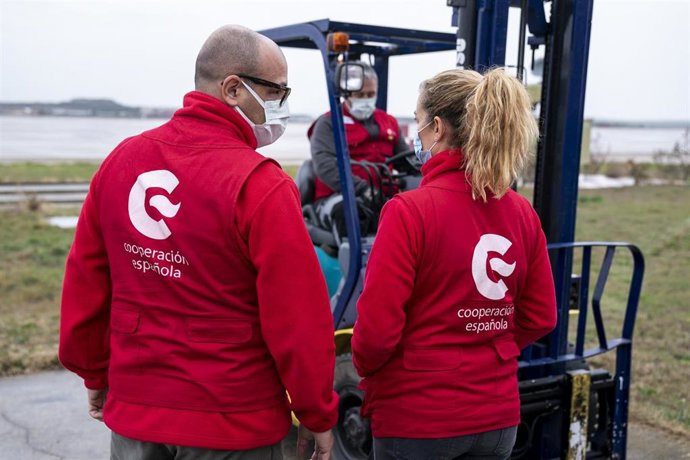 Archivo - Un operario, en grúa, y personal de la AECID, durante la recepción de material sanitario  para mandar a Ucrania, en la Base Aérea de Torrejón de Ardoz