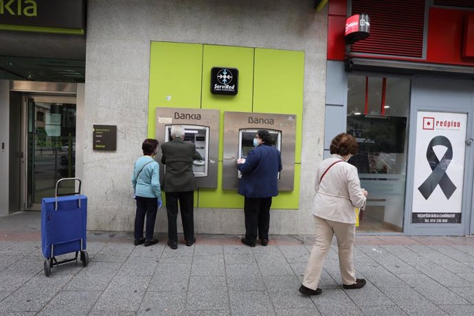 Archivo - Personas mayores sacan dinero en un cajero de Bankia