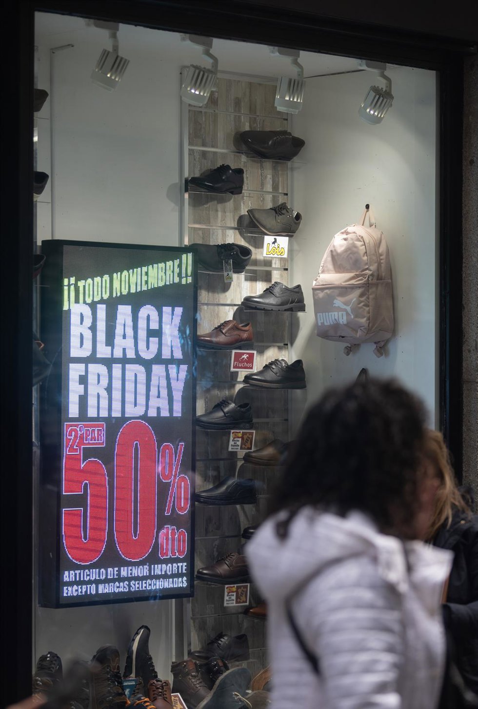 Una persona pasa por delante de una tienda que anuncia un cartel publicitario del Black Friday,