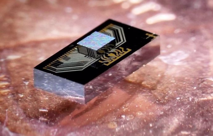 El sándwich de chip: un chip electrónico (el chip más pequeño en la parte superior) integrado con un chip fotónico, colocado encima de un centavo a modo de escala.