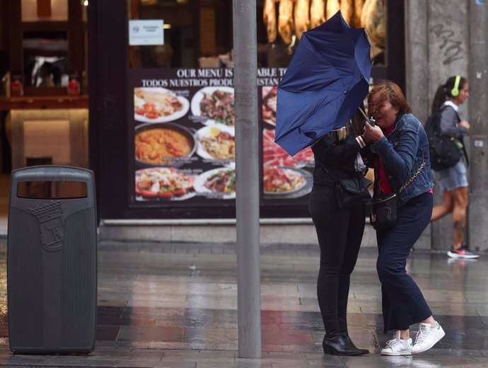 Archivo - Dos chicas intentan controlar su paraguas, en la calle Gran Vía, a 20 de octubre, en Madrid (España). 