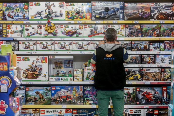 Archivo - Un empleado coloca juguetes de un pasillo en una tienda de juguetes.