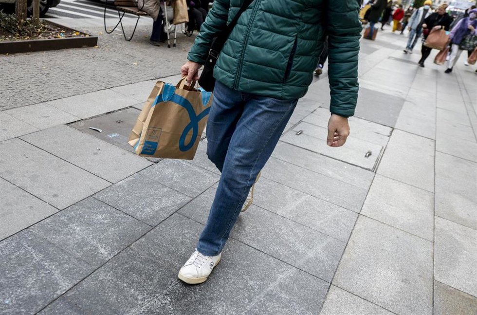 Archivo - Un hombre camina con una bolsa con compra de un comercio.